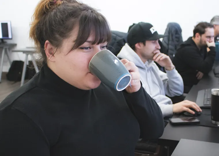Femme avec tasse grise assise au bureau / Woman with grey mug sitting at desk