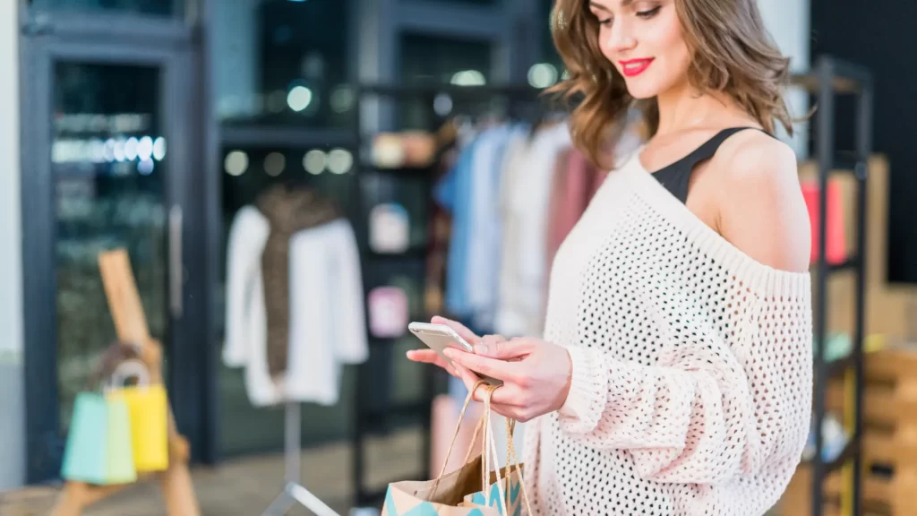 une femme dans un magasin utilise son mobile pour des infos. Une expérience phygital à Terrebonne