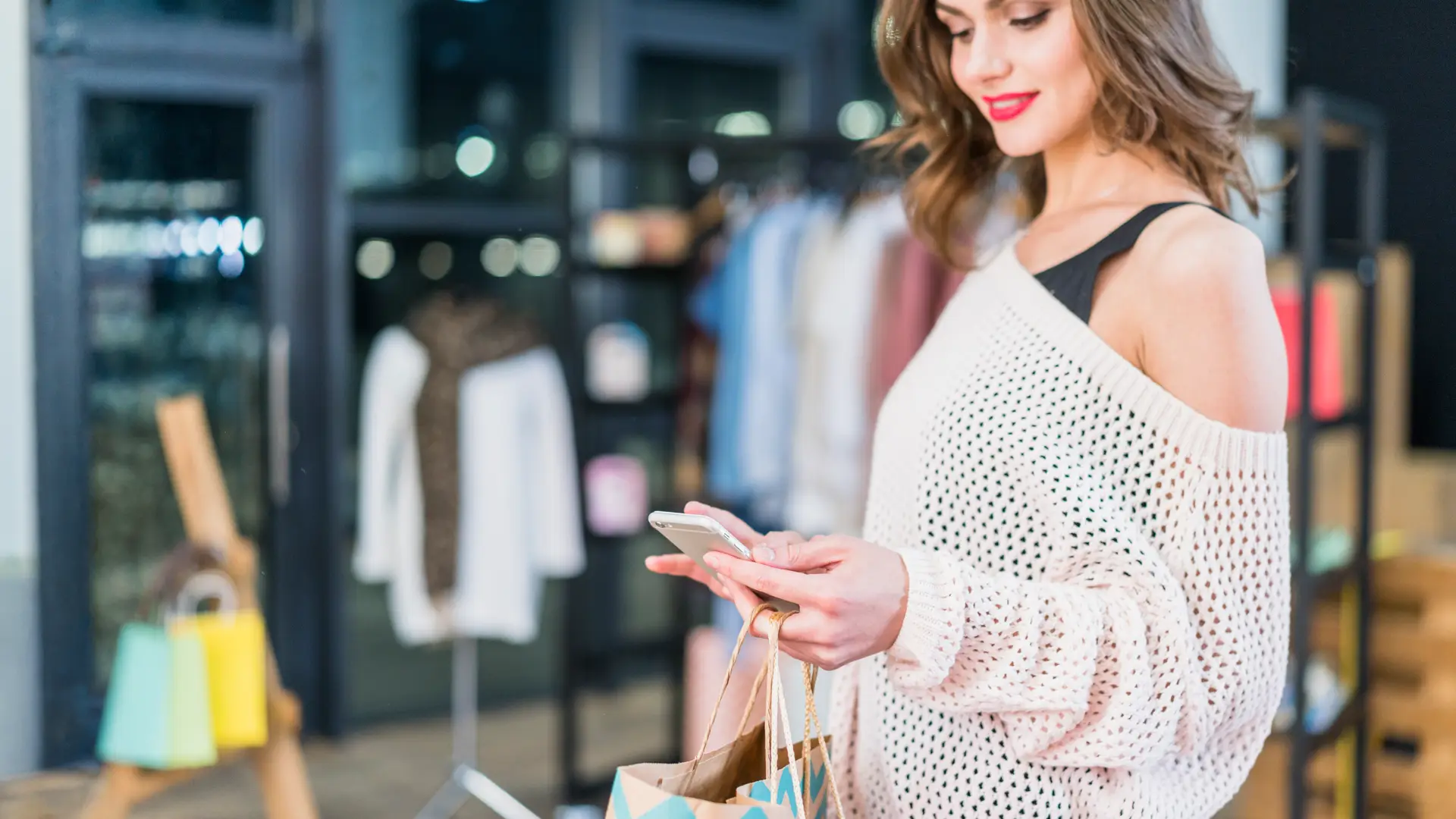 une femme dans un magasin utilise son mobile pour des infos. Une expérience phygital à Terrebonne